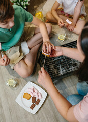 Top view of family preparing s'mores with small barbecue at home