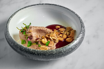 Restaurant pate with berry sauce, peanuts and microgrin in a marble plate with toast in a metal basket on a white marble background