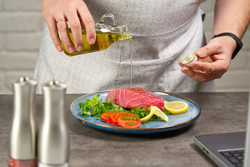 Cooking with notebook tuna steak in home kitchen. Online cooking recipe concept, fish cooking at home. lifestyle, healthy eating, cooking and dieting concept.