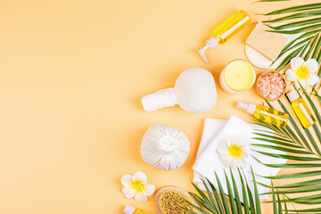 Spa massage Aromatherapy body care background. Spa herbal balls, cosmetics, towel and tropical leaves on orange table. Top view, flat lay, overhead, copy space. Beauty and health care concept