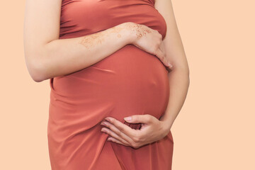 pregnant woman supports her belly with her hands, close-up