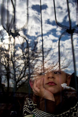 the child staying at home due to covid. child looking out the window