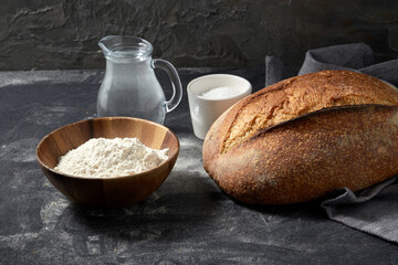food, baking and cooking concept - homemade craft bread, wheat flour, salt and water in glass jug on table