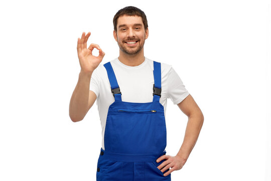 profession, construction and building concept - happy smiling male worker or builder showing ok hand sign over grey background