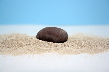 Fototapeta na wymiar Sea round stones on the fine sand. Selective focus.