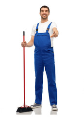 profession, service and people concept - happy smiling male worker or cleaner in overall cleaning floor with broom over white background