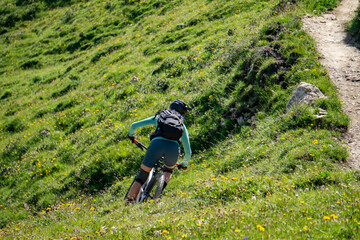 Girl with a endurobike on a single trail between graas and flowers
