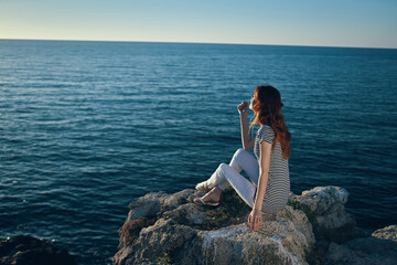 the traveler sits on the beach near the sea in the mountains and sunset
