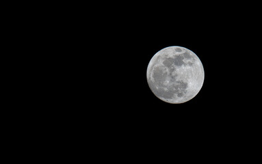 Full moon over dark black sky at night. Selective focus