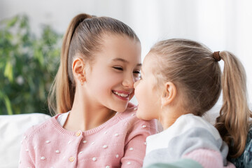 family, childhood and friendship concept - two happy smiling little girls or sisters at home