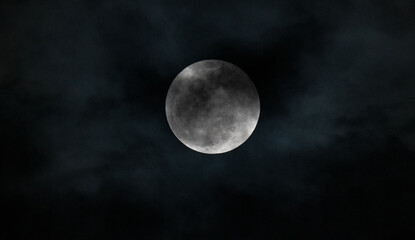 Full moon over dark black sky with clouds at night. Selective focus