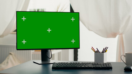 Powerful computer with chroma key green screen mock up stands on desk in living room. Pc with isolated display in home office with nobody in is ready for online business meeting
