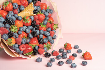Edible bouquet of fresh berries, blueberries, raspberries, strawberries, hedgehog on a pink background with scattered berries. View from the top .Close-up .Concept of a useful gift, 
