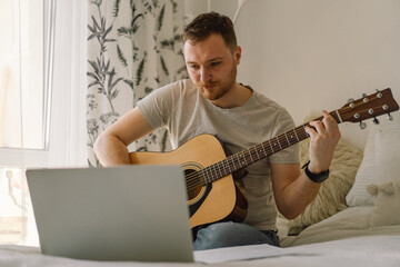 Man plays an acoustic guitar in an online lesson. Hobby a musician.