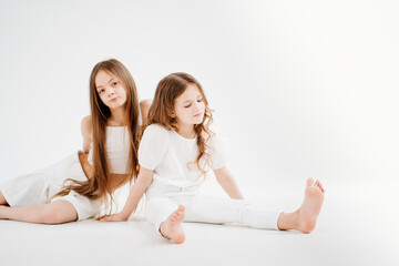 Fototapeta na wymiar two little girls with long hair in white clothes. love between sisters. 