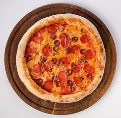 Top view of hot pizza on a wooden stand.