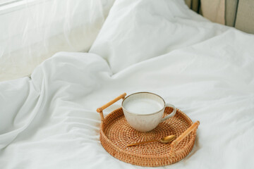 Fototapeta na wymiar Breakfast in bed, cappuccino, wicker tray, spring, home decor. Cozy.