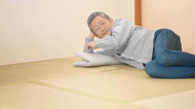 寝っ転がりながらテレビを見るシニア男性