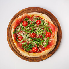 Top view of hot pizza on a wooden stand.