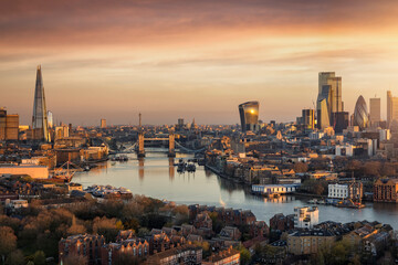Panoramic, aerial view to the urban skyline of London during a golden sunrise with Tower Bridge and the skyscrapers of the City district, United Kingdom