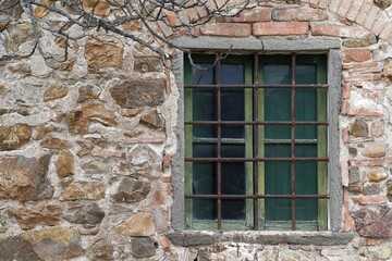 Fototapeta na wymiar window with broken glass of old abandoned and dilapidated stone house in the Tuscan countryside in Italy