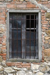 window with broken glass of old abandoned and dilapidated stone house in the Tuscan countryside in Italy