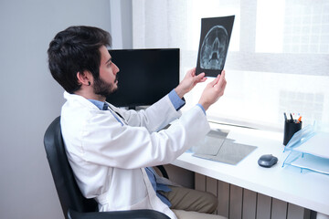 Young doctor examining x-ray of the skull, sinuses. Radiography of a head.