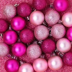 Christmas balls on a pink glittering background. Festive monochrome texture.