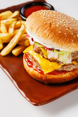 Burger. Juicy pork cutlet, cheddar cheese, crispy pickled onions, lettuce wrapped in a bun under two sauces. Served with french fries and cream sauce.