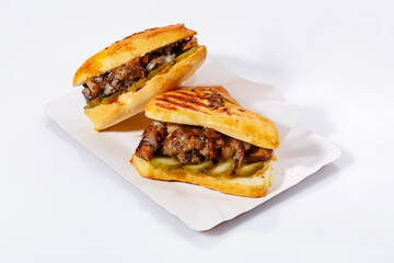 Street food sandwiches with meat, pickled cucumbers on a white plate. White background. Side view.