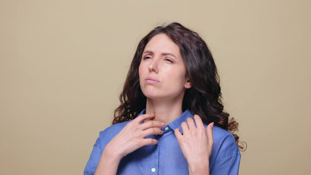 Portrait of millennial casual woman suffer from heat, lack of air. Exhausted young female wave hand unbutton shirt feel bad of heatstroke or stressful situation. Overheated girl at beige studio wall