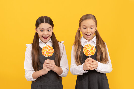 Super yummy. Candy girls yellow background. Suprised kids hold candy lollipops. School snack