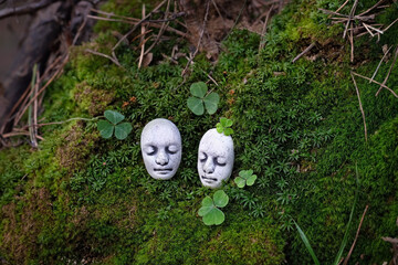 mystery stone faces on dark moss natural background with clover leaves. Fantasy mystical image of...