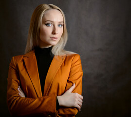 Portrait of beautiful young woman in orange blazer. Studio shot.