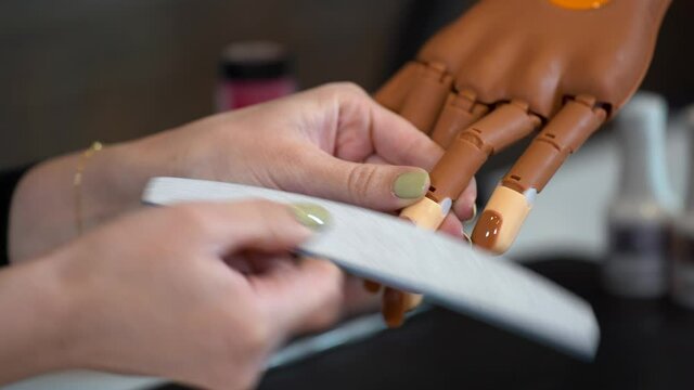Manicure creates the correct shape of nails on a prosthetic hand with a Nail file (education)