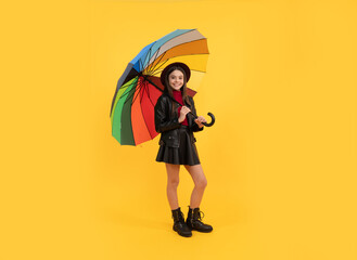 happy teen girl in hat and leather clothes under rainbow umbrella, autumn