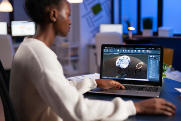 Tired african designer engineer analyzing new prototype of 3D model of industry product, working overtime. Industrial female worker studying gears idea on laptop showing cad software on device display