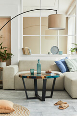 Stylish scandinavian living room interior with neutral modular sofa, design coffee table, window, floor lamp, plant, decoration, carpet and personal accessories in modern home decor. Template.