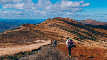 Fototapeta na wymiar Group of People Hiking Autumn Mountain Trail Path under the clouds