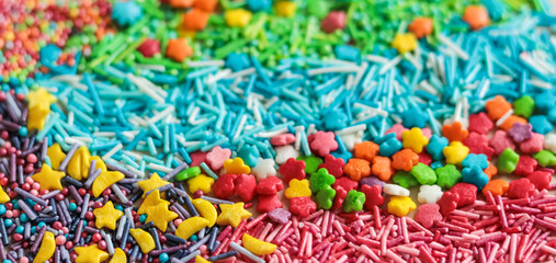 Abstract background of multicolored sugar sprinkles of different shapes for decorating glazed pastries