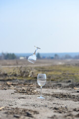 пустой винный бокал стоит на земле на фоне пейзажа над ним левитирует бокал
