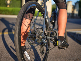 Close up view on wheel and chain of road bike. Professional cyclist riding a bicycle in park on a sunny day