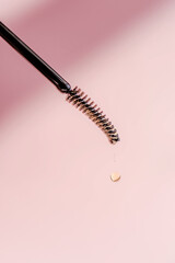 A drop of oil for eyebrows and eyelashes falls from the brush