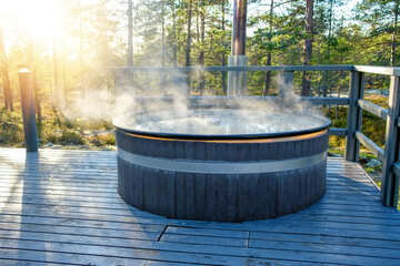 Modern big barrel outdoor hot tub in the middle of forest. The hot tub's soothing warm water...