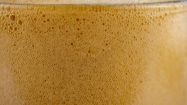 foam of dark beer in a glass glass, macro photography, backgrounds, textures