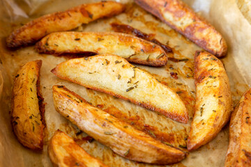 Homemade Rosemary Potato Wedges on a baking tray, side view. Close-up.
