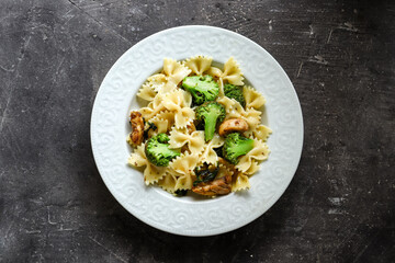 Farfalle with broccoli and chicken and basil. Italian food. Top view. Dark background. Isolated. Copy space.