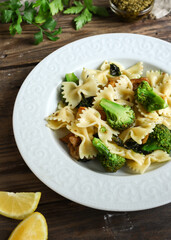 Farfalle with broccoli and chicken and basil. Italian food. Close up. Wooden background. Copy space.