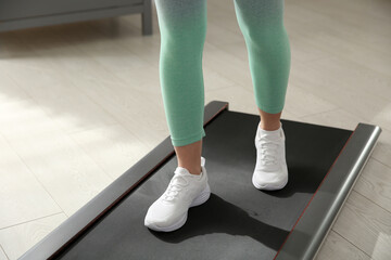 Sporty woman training on walking treadmill indoors, closeup