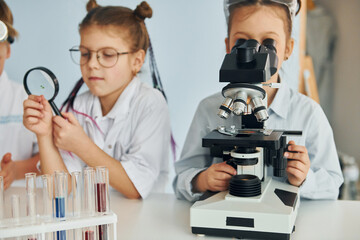 Children in white coats plays a scientists in lab by using equipment